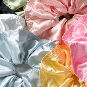 Lustrous satin oversized scrunchies in vibrant pastel colors with elegant pleated details