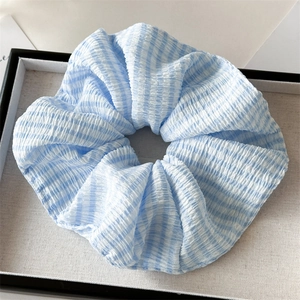 Detail of blue and white checkered scrunchie with pleated texture on white fabric base