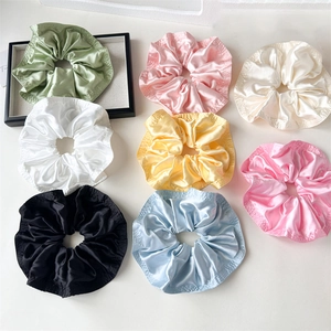 Detail showing eight pastel colors of large satin scrunchies with elegant ruffled edges