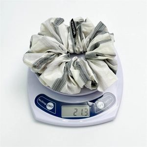Detailed view of checkered fabric scrunchie on electronic scale weighing 21.3 grams
