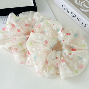 Close-up of beige mesh scrunchies with colorful polka dots in a lifestyle aesthetic setting