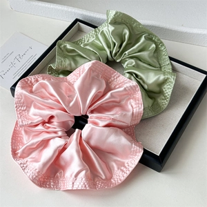 Set of two large satin scrunchies in pink and green with ruffled edges on display tray