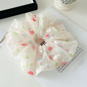 Detail of light mesh hair scrunchie with colorful large polka dots on white background