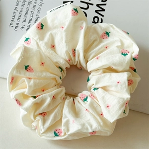 Nahaufnahme von Erdbeer-Blumen-Scrunchie mit weichem Stoff und angenähtem Markenetikett