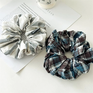 Close-up of handmade striped and plaid fabric scrunchies with elegant cloth labels