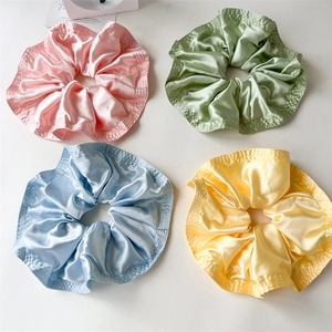 Detail of four colorful satin scrunchies with elegant quilted edges on white background