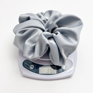 Detail van een grote grijze satijnen scrunchie van 35,6 g op een digitale weegschaal