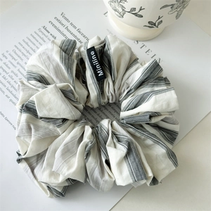 Detailed view of large pleated grey striped hair scrunchie with Miniline woven label