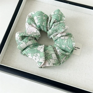 Détail d'un chouchou en mousseline fleurie avec motif tie-dye vert et texture du tissu