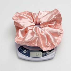 Pink satin scrunchie with pleated design on digital scale showing weight of 16.6g