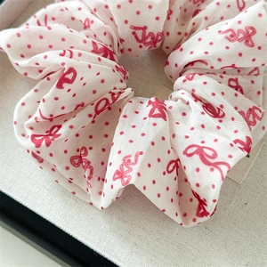 Gros plan d'un chouchou à pois rouges et blancs avec une texture de tissu en mousseline