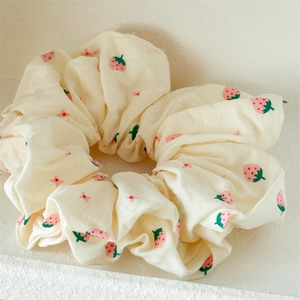 Nahaufnahme von flauschigem cremefarbenem Scrunchie mit rosa Erdbeer- und Sternenmustern