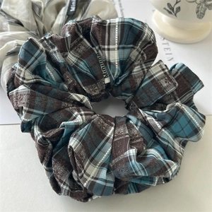 Detail of blue and brown checkered fabric hair scrunchie with white Miniline brand label