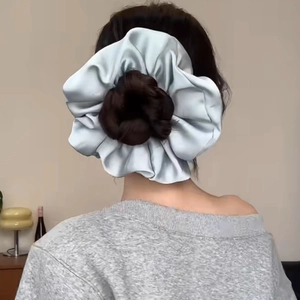Detailweergave van een grote lichtblauwe satijnen scrunchie gedragen in een zacht kapsel
