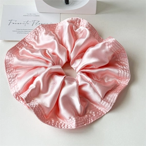 Detailed close-up of pink satin scrunchie showing smooth texture and ruffled design