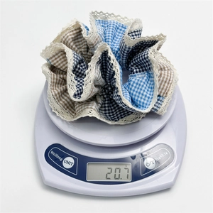 Macro detail of large blue patchwork plaid scrunchie with lace trim on a scale