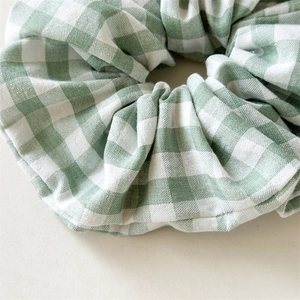 Détail rapproché du chouchou en tissu à carreaux verts et blancs à texture souple