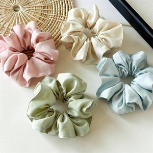 Détail de quatre chouchous en coton tencel aux tons pastel rose, beige, vert et bleu clair