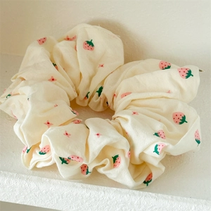 Detail eines cremefarbenen Scrunchies mit Erdbeermustern und rosa Blumendruck