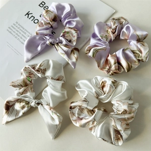 Detail of four-piece satin floral scrunchie set in light purple and beige tones