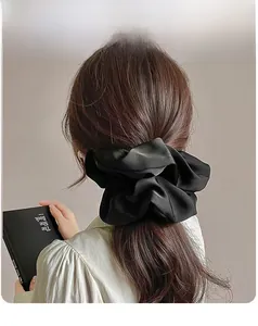 Detailed back view of a large black satin scrunchie styling a low ponytail hairstyle