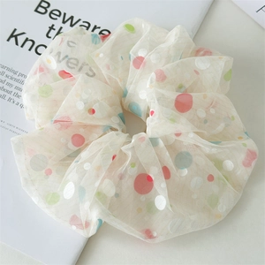 Close-up of large cream mesh scrunchie with colorful polka dots on a minimalist magazine