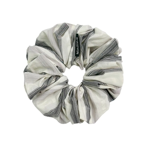 Plaid pleated fabric scrunchie in beige and grey stripes with a woven side label