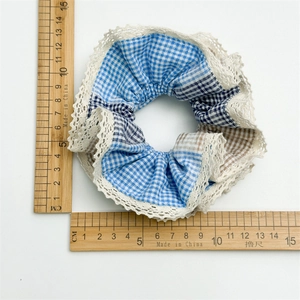 Blue and white plaid oversized scrunchie with lace edge shown next to wooden rulers