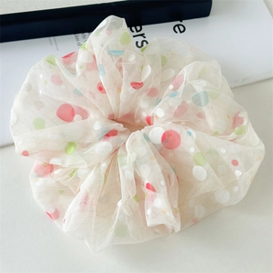 Detail of 18cm large mesh scrunchie featuring vibrant colorful polka dots on beige fabric