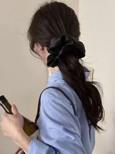 Detailed view of a black satin oversized scrunchie on a ponytail with silky texture