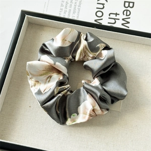 Detail of floral satin scrunchie with silky sheen on a minimalist display tray