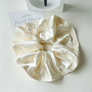 Close-up of cream satin oversized scrunchie with detailed lattice weave texture edge