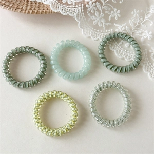 Vue détaillée de cinq élastiques spirales verts avec motifs de cœurs et de damiers pour cheveux