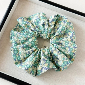 Détail du chouchou fleuri vert montrant la texture du tissu et le motif plissé élégant