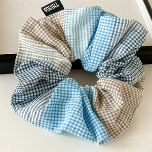 Detail of blue plaid patchwork scrunchie featuring a premium fabric texture and woven tag