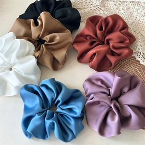 Close-up of premium satin scrunchies showing smooth silk texture and assorted colors
