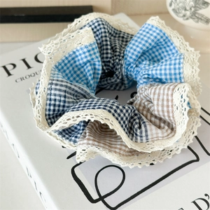 Detail view of blue and brown checkered fabric scrunchie with delicate lace trim