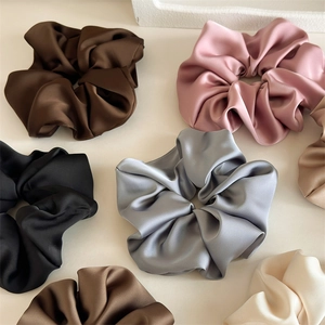 Close-up of assorted satin silk scrunchies in coffee, pink, blue, and champagne tones