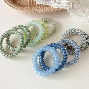 Détail d'élastiques à cheveux en spirale de couleurs bleu, vert et à motifs damiers