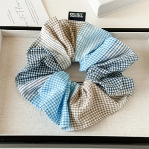 Detail of oversized blue patchwork scrunchie featuring checkered fabric and brand label