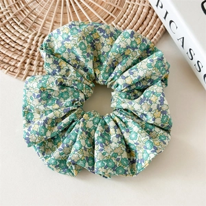 Détail d'un chouchou à fleurs vertes avec coutures nettes et texture élastique