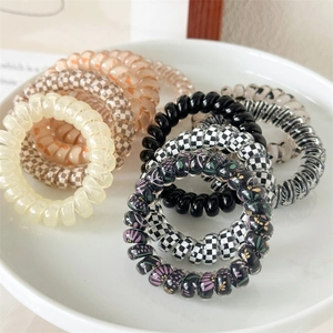 Détail d'élastiques à cheveux spirales avec motifs à carreaux et floraux