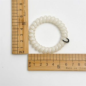 Vue détaillée du diamètre de 5 cm d'un chouchou spirale blanc de type fil de téléphone