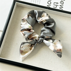 Detailed macro view of satin floral bow scrunchie with rabbit ear design on linen tray