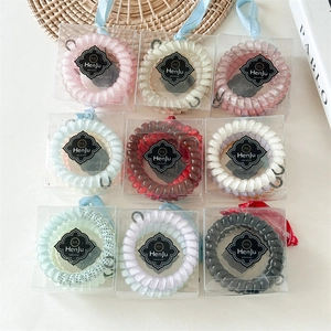 Détail d'élastiques à cheveux spirale colorés présentés dans des boîtes cadeaux individuelles