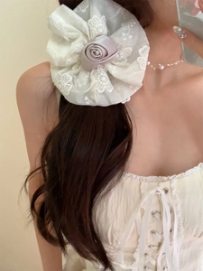 Détail d'un chouchou en dentelle blanche élégant avec une rose en satin mauve délicate