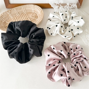 Close-up of elegant satin scrunchies set with heart pattern in black white and pink