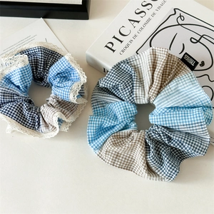Detail of blue plaid oversized scrunchies with white lace trim on artistic background