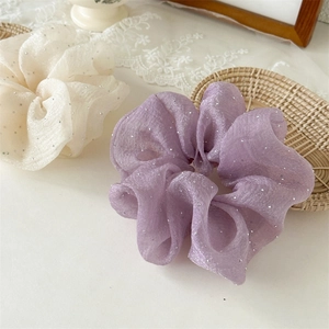 Détail de chouchous en tulle crème et violet avec strass dans un décor romantique