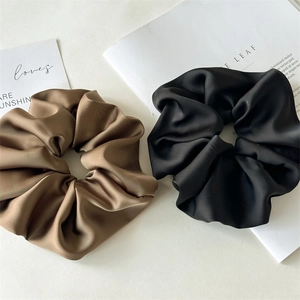 Close-up of brown and black satin scrunchies with elegant glossy texture and soft folds